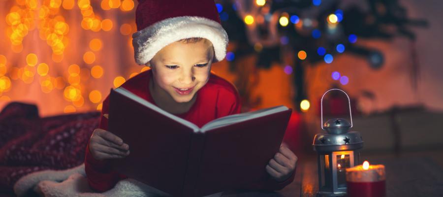 Child reading by the Christmas tree