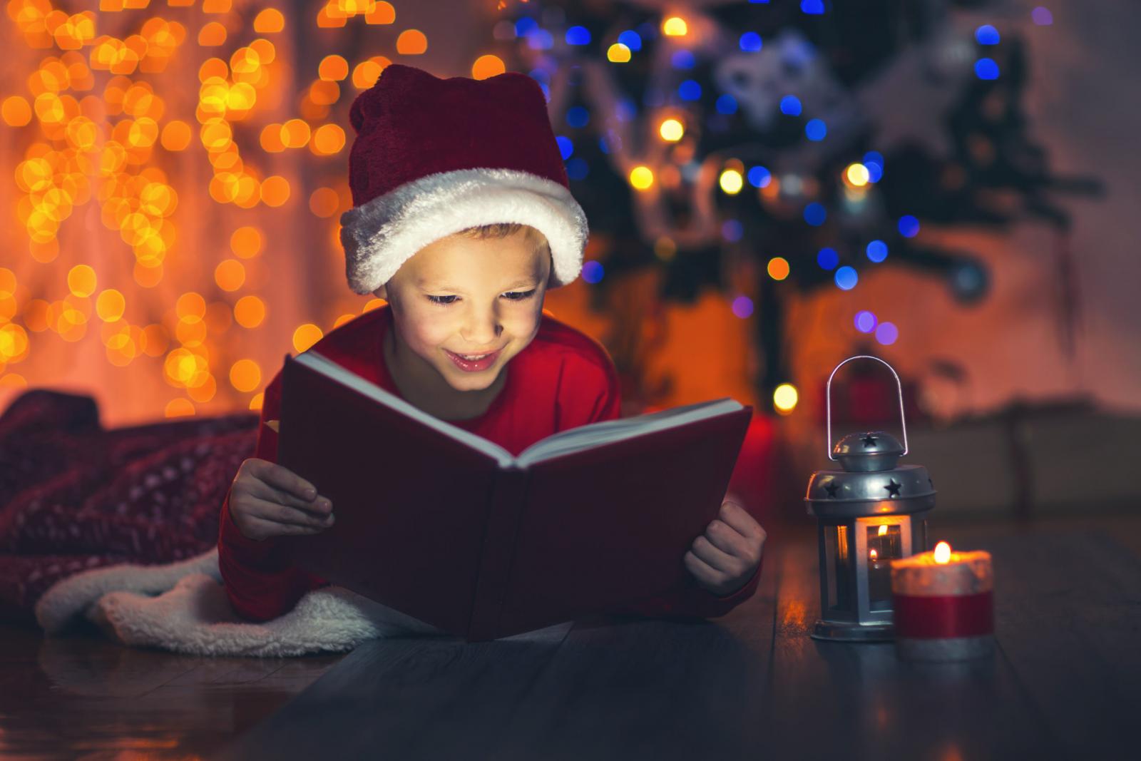 Child reading by the Christmas tree